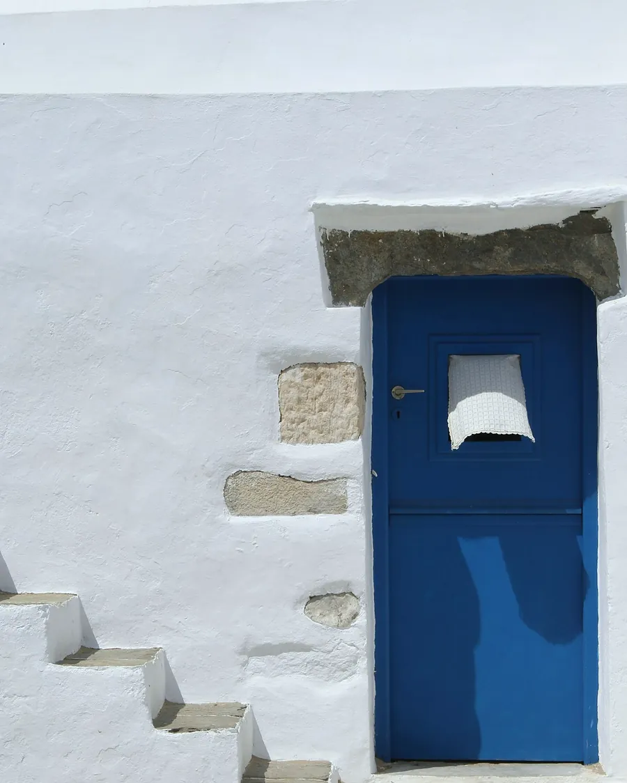 A white house with a blue door and steps built into the wall