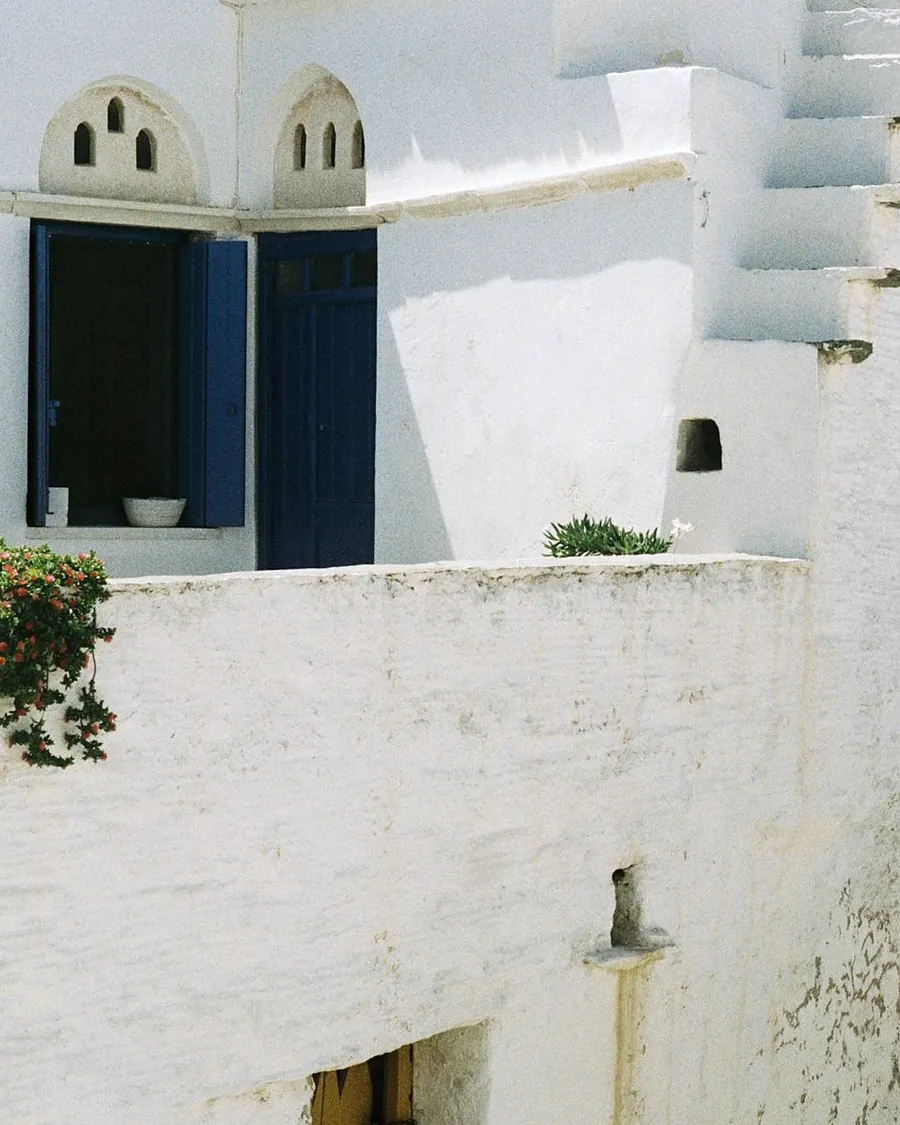 Whitewashed rooftops and a blue window across the lane