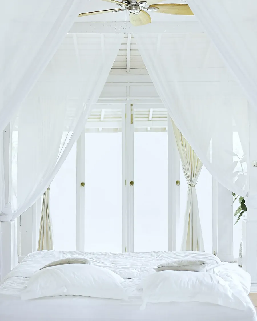 White curtains open onto a bright bedroom with tall glass doors