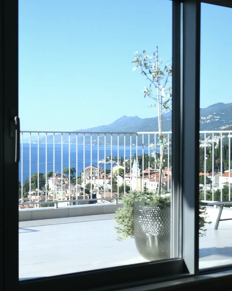 The sea and the town seen through a tall glass door onto a terrace
