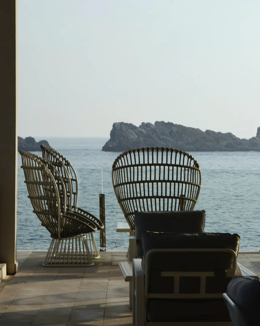 Two cane chairs on the roof terrace facing the sea and a rocky island