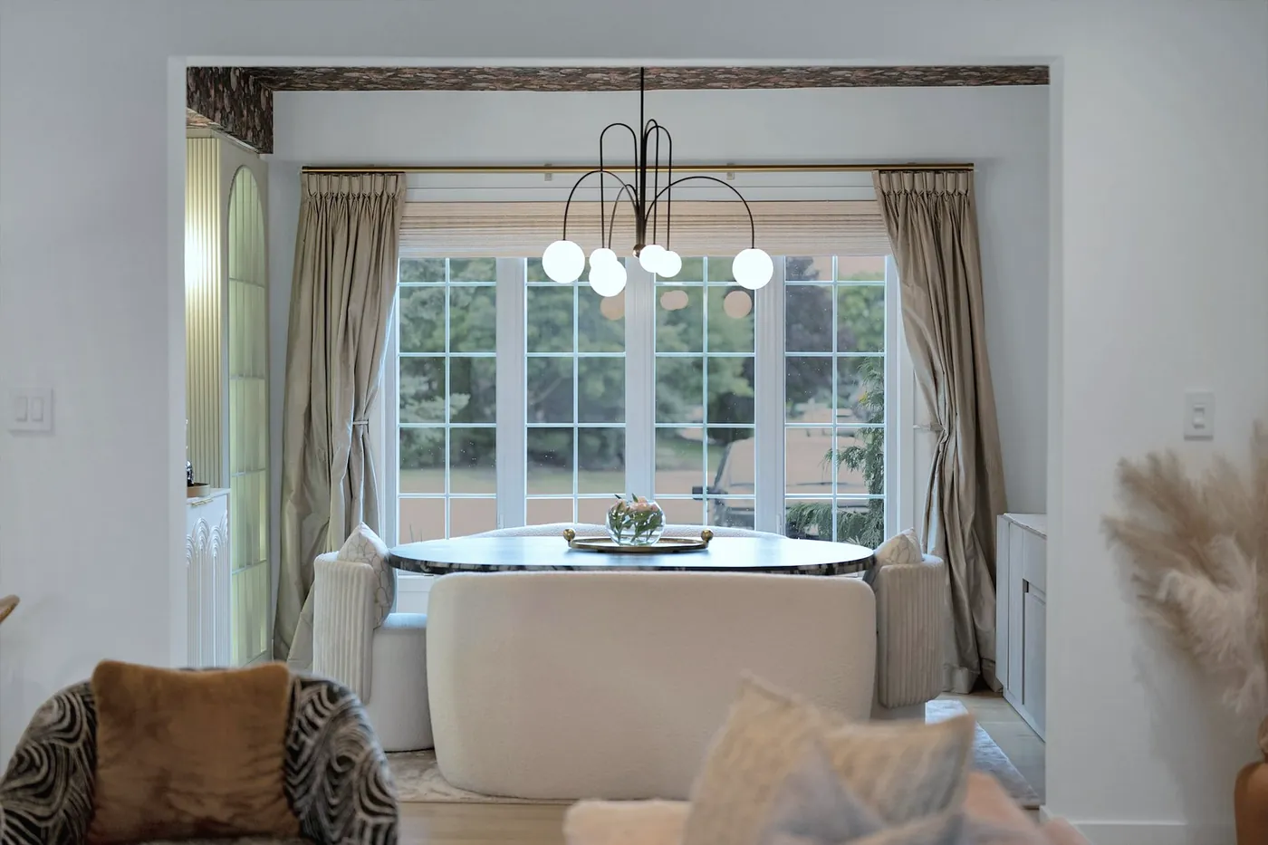 Sitting room with a round table in a bay window, a low sofa and soft chairs