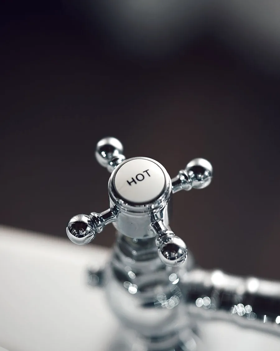 A chrome bathroom tap with a hot label on the handle