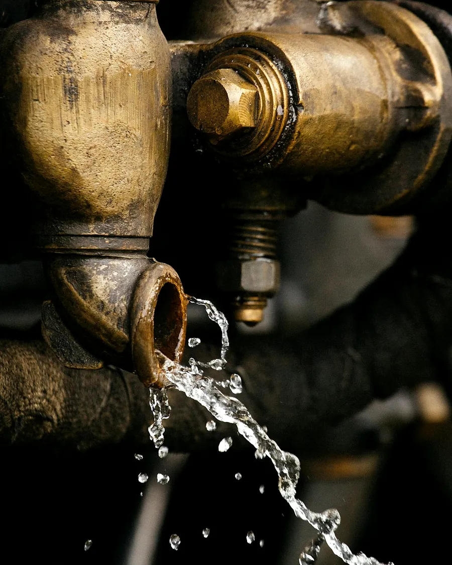 Water spraying from a joint in an old brass pipe