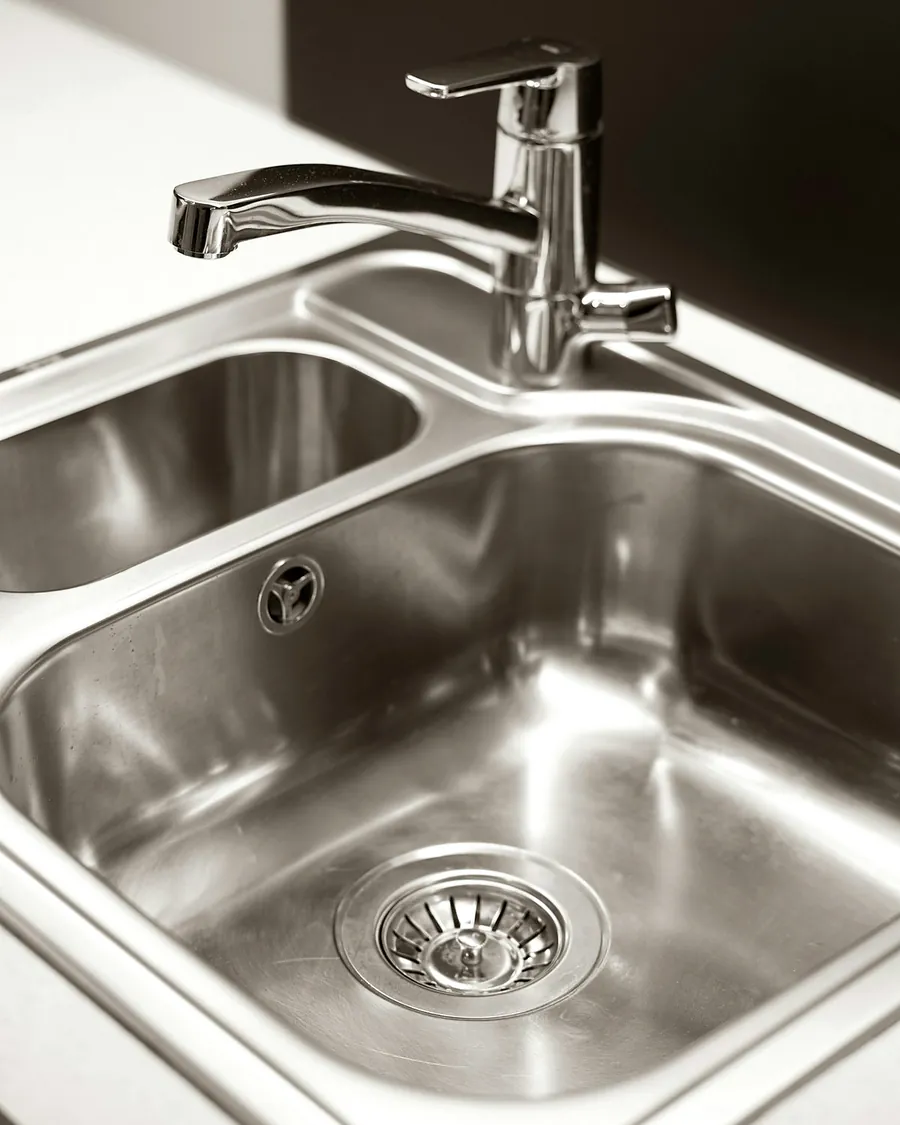 A stainless steel kitchen sink with a chrome mixer tap