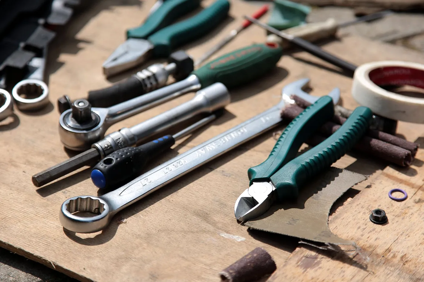 Spanners, pliers and a ratchet laid out on a plywood van floor
