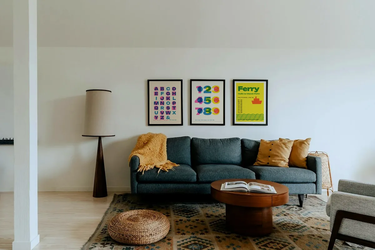 Three framed posters above a blue sofa in a living room.