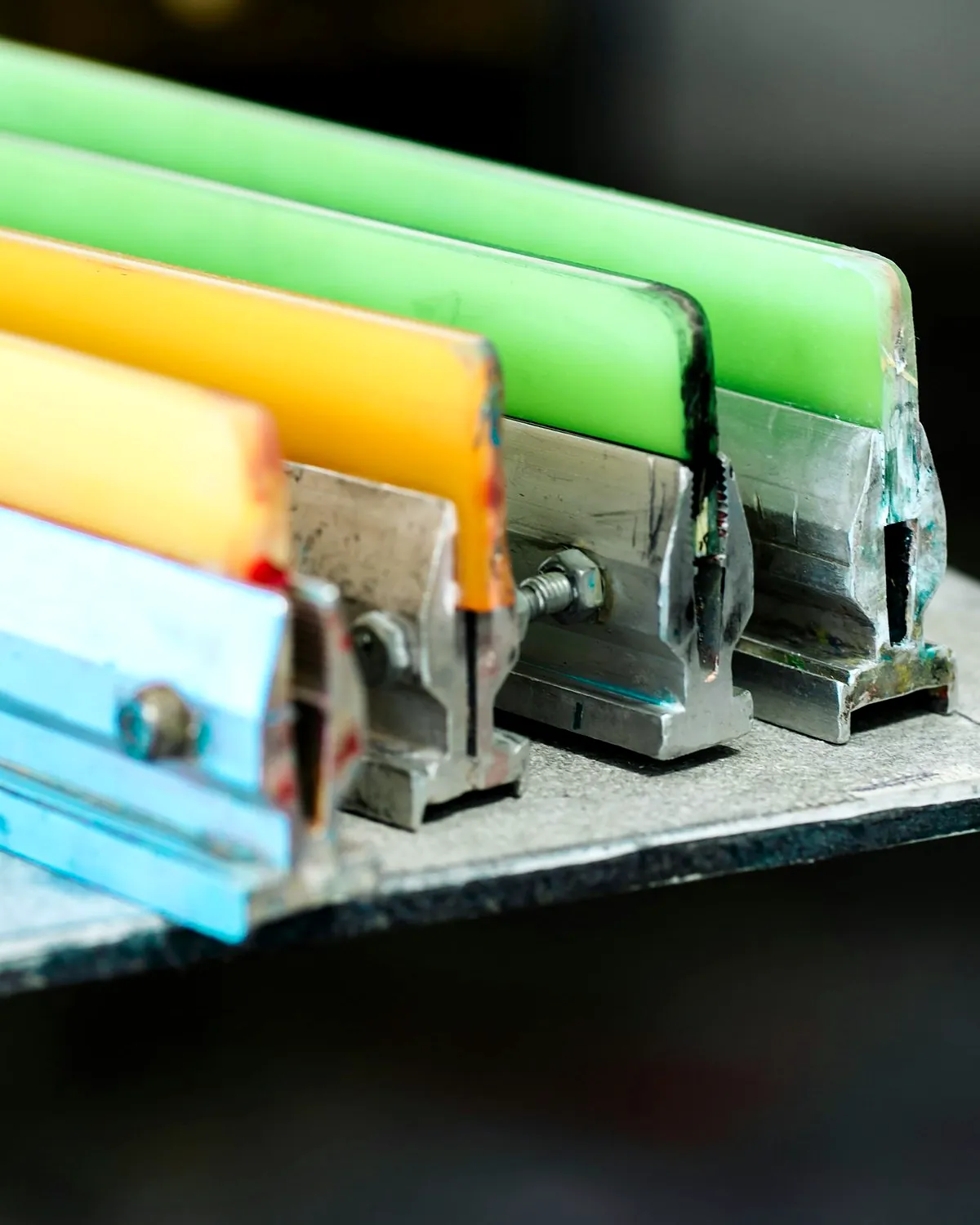 Squeegees with green, yellow and blue blades in a rack.