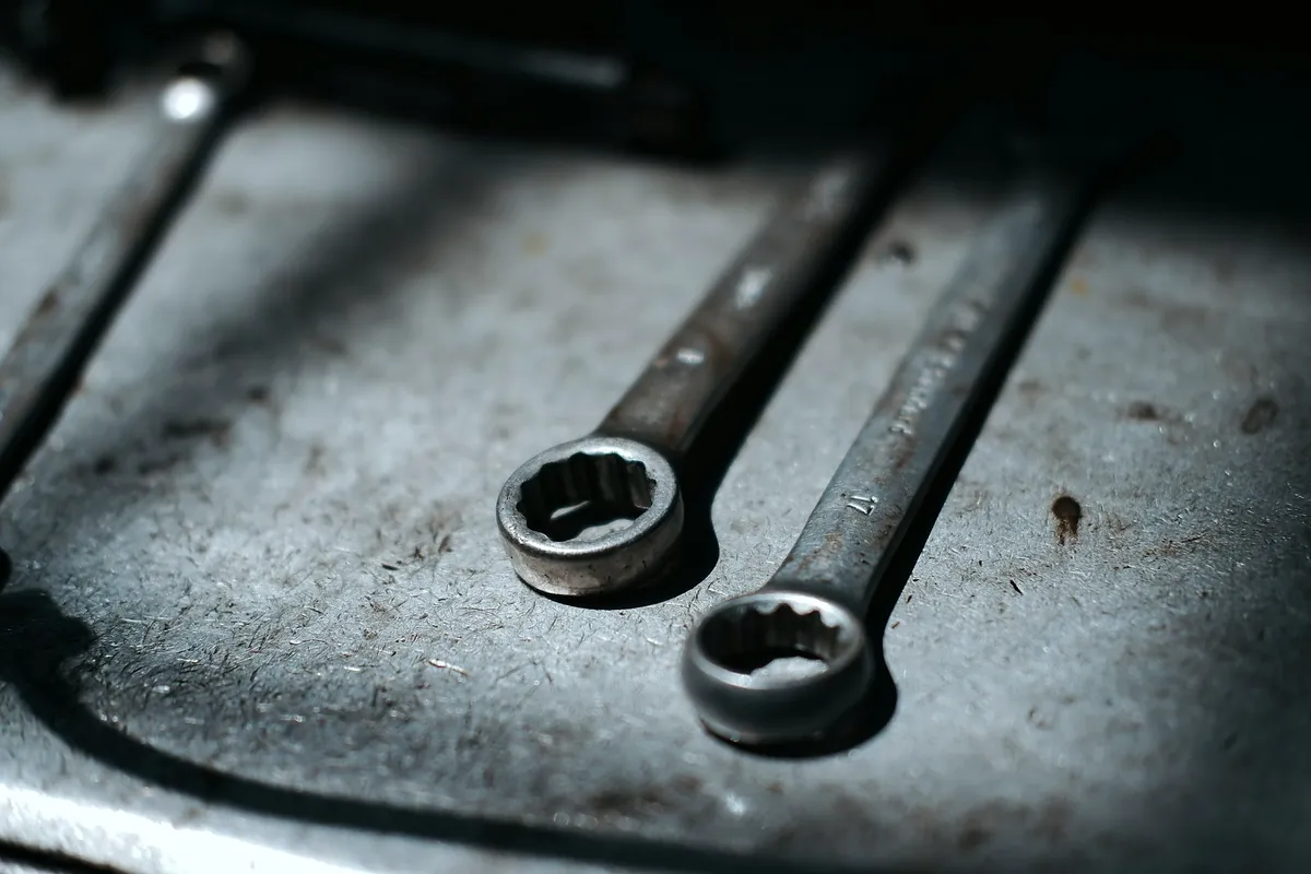 Two ring spanners on a steel workbench