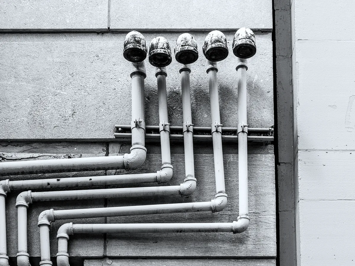 White plastic waste pipe runs on a workshop wall.