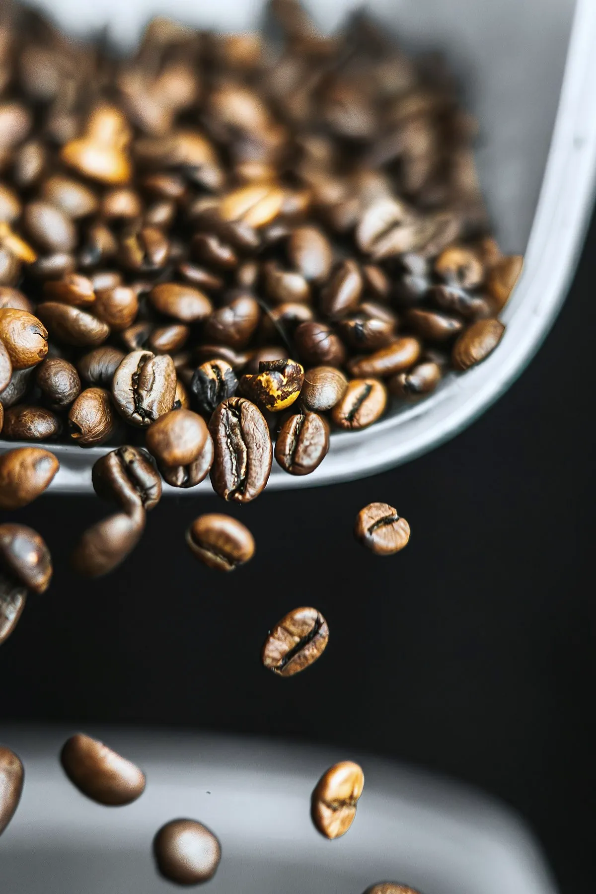 Freshly roasted beans pouring from a metal scoop