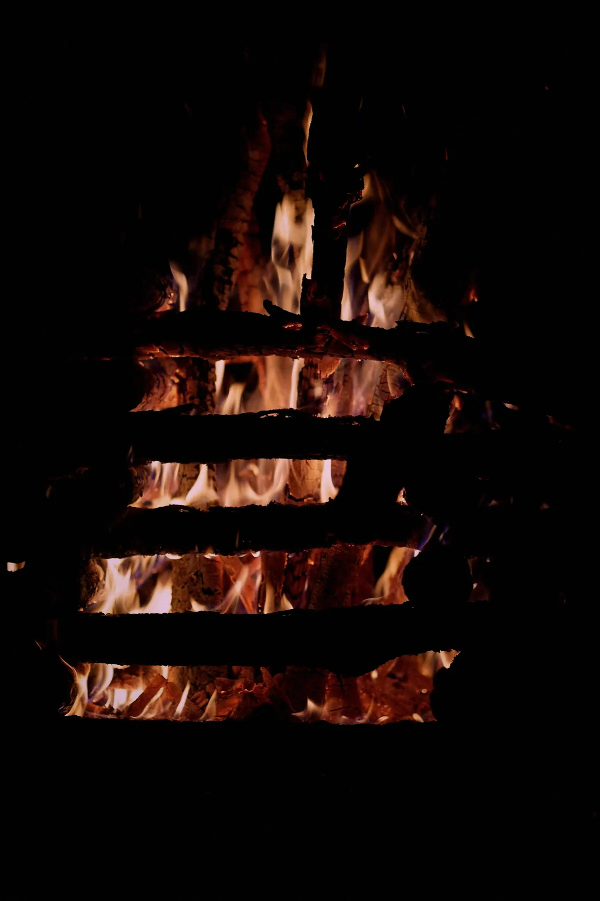 Flames showing between the bars of a fire grate in the dark