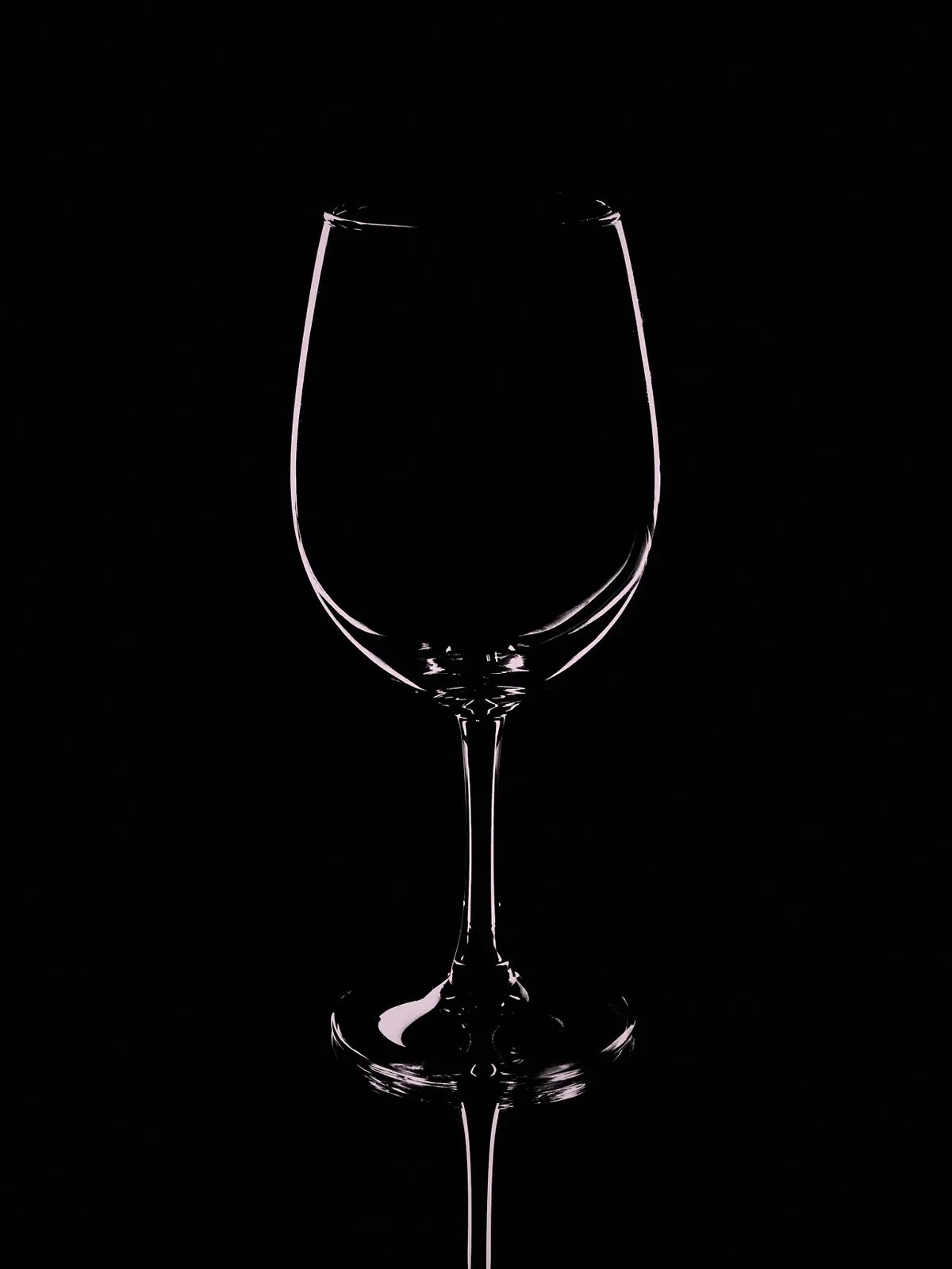 An empty wine glass lit from the side on black