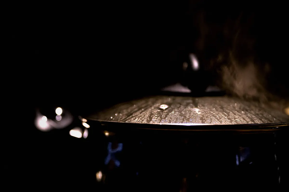 Steam escaping from under the lid of a cast iron pot
