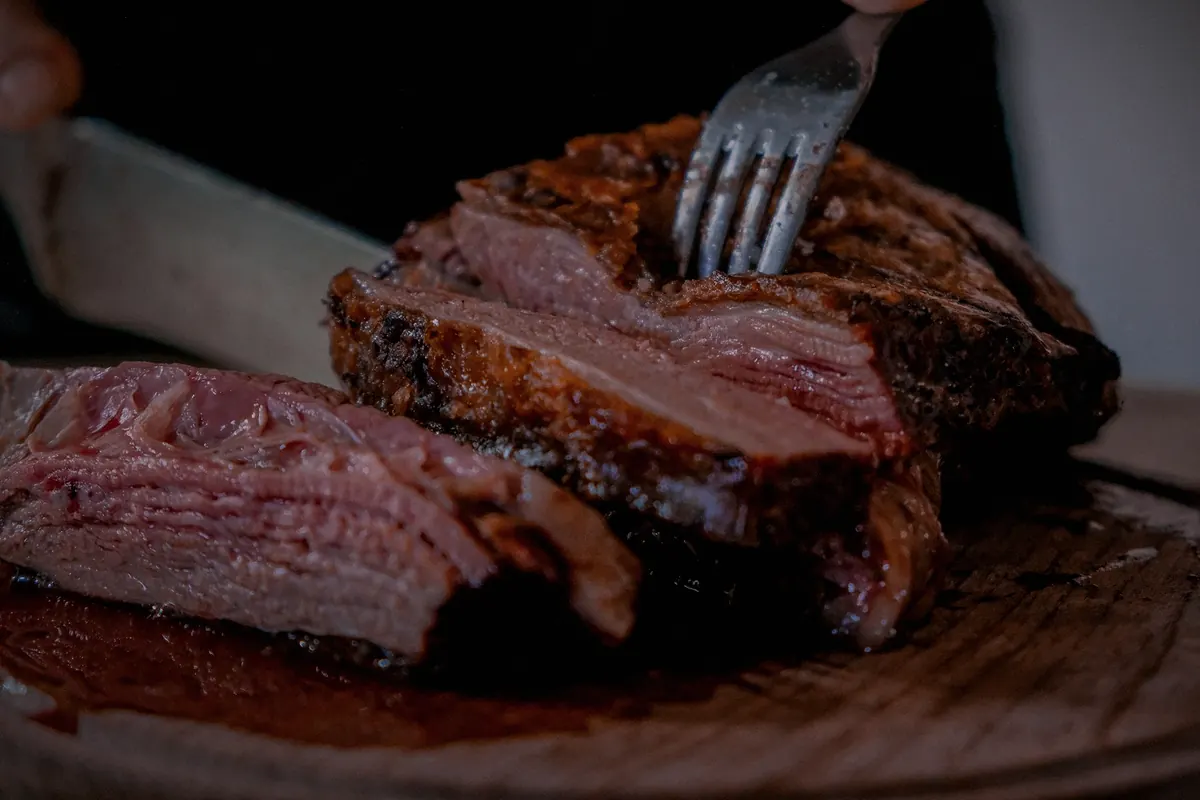 Slices of rare beef being cut on a wooden board