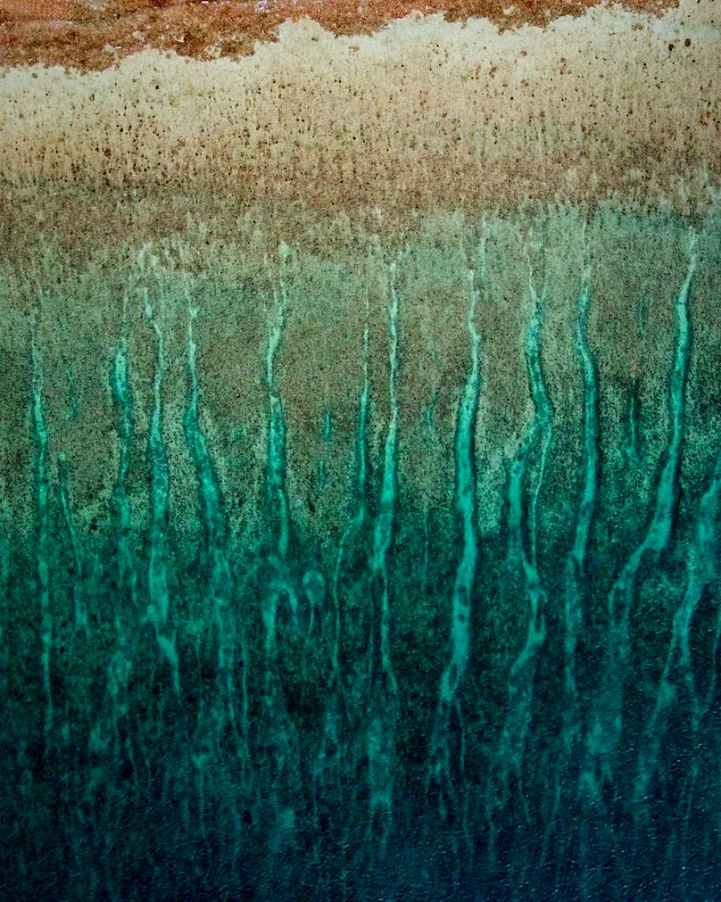 A close view of copper teal glaze running in streaks over a pale rim