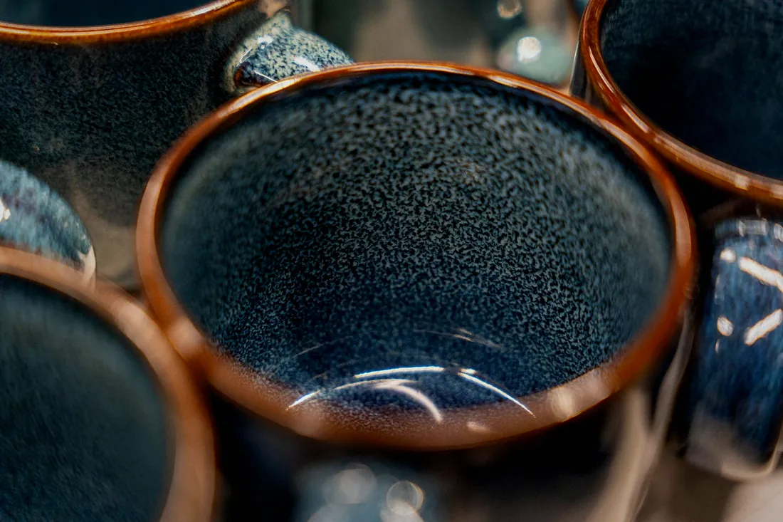 Cups seen from above, their insides glazed dark blue with speckles and rust brown rims