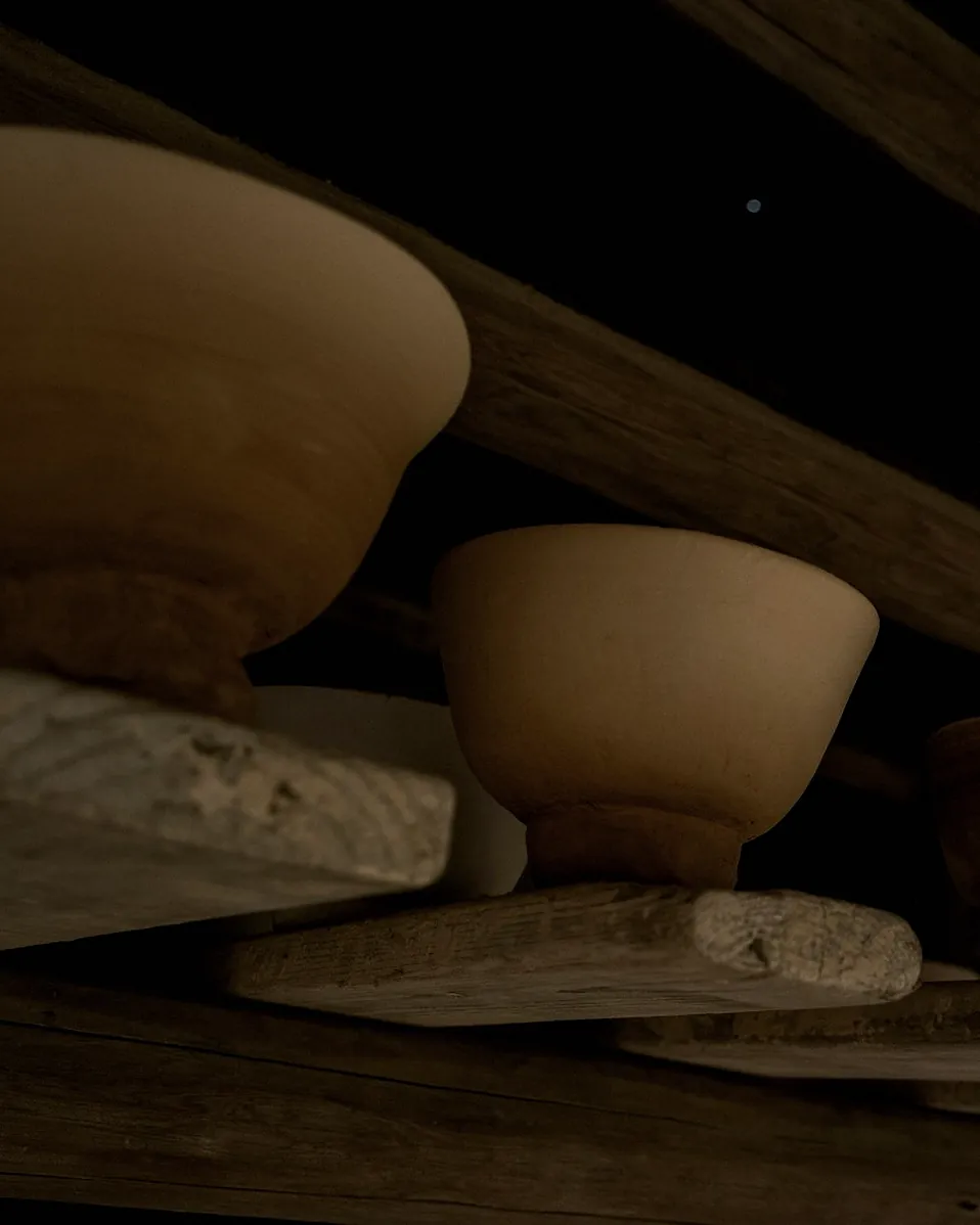 Unfired bowls drying on wooden shelves
