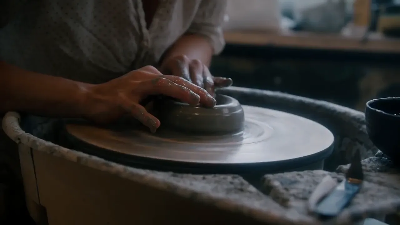 Video still at 0:00. The clay is centred and opened into a low ring