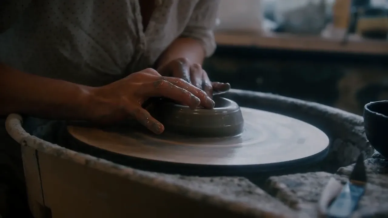 Video still at 0:03. Fingertips press the rim down so it stays level while the wheel turns