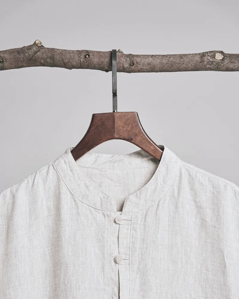 Close view of the band collar and two buttons of the oat linen shirt on its hanger