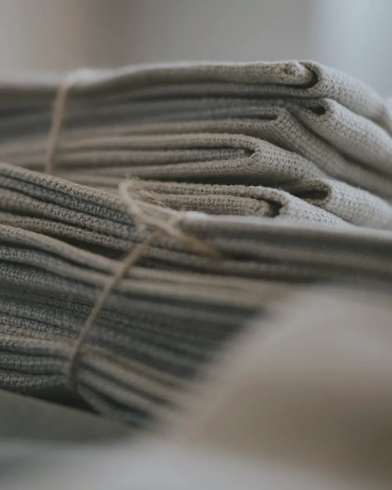 A stack of folded stone grey linen napkins tied with string