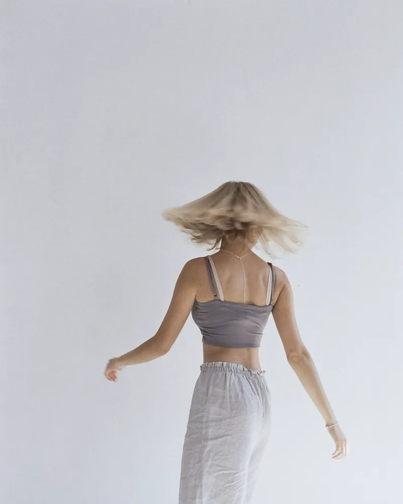 The pale grey wide trousers from the back, the woman turning with her hair flying