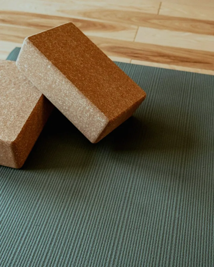Two cork blocks resting on a green mat on a wooden floor