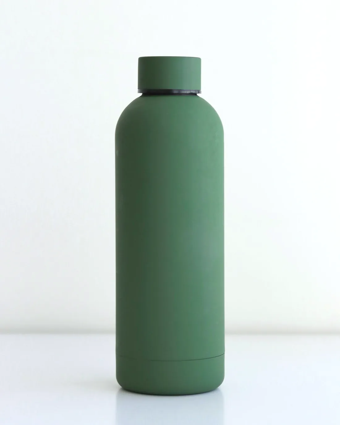 A sage green steel water bottle on a white table