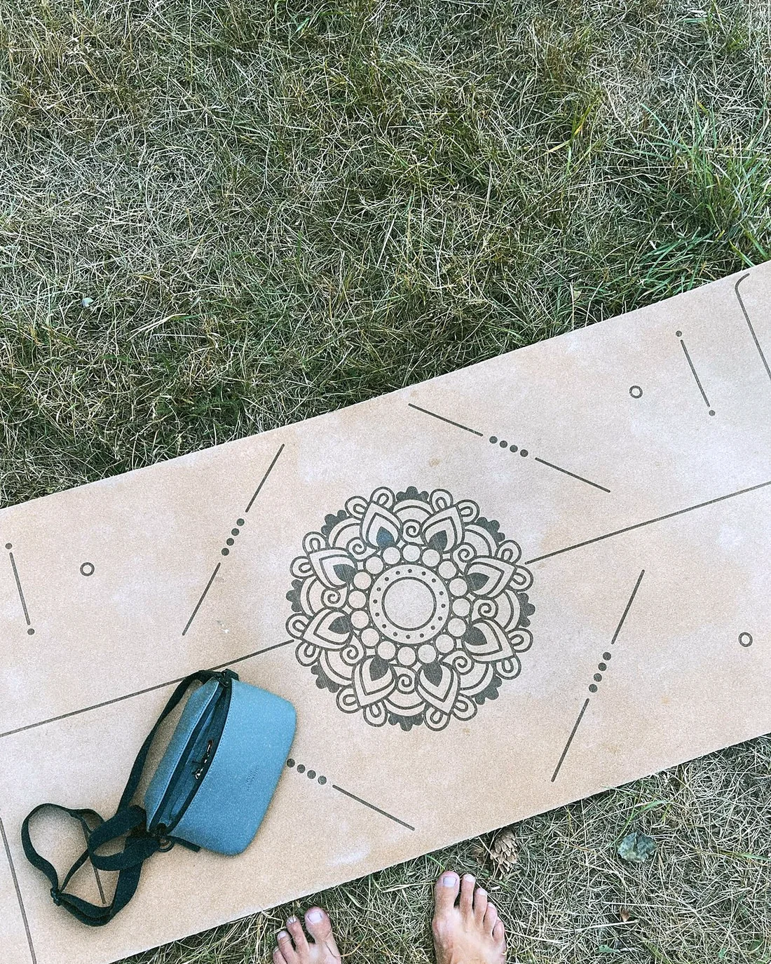 A cork yoga mat with printed lines and a round mark in the middle, laid on grass
