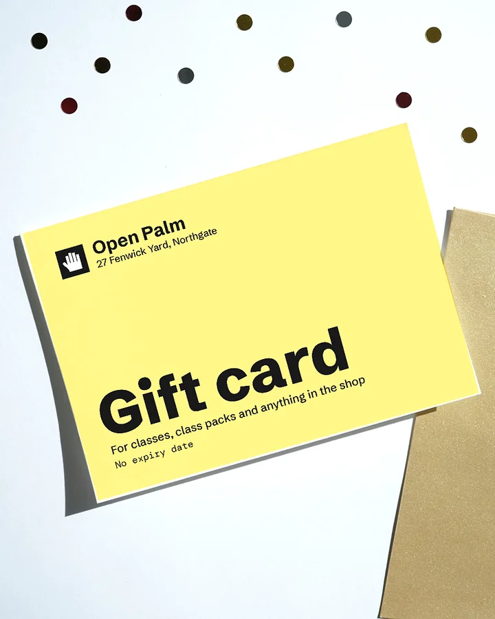 A yellow Open Palm gift card on a kraft envelope, with confetti on a white table