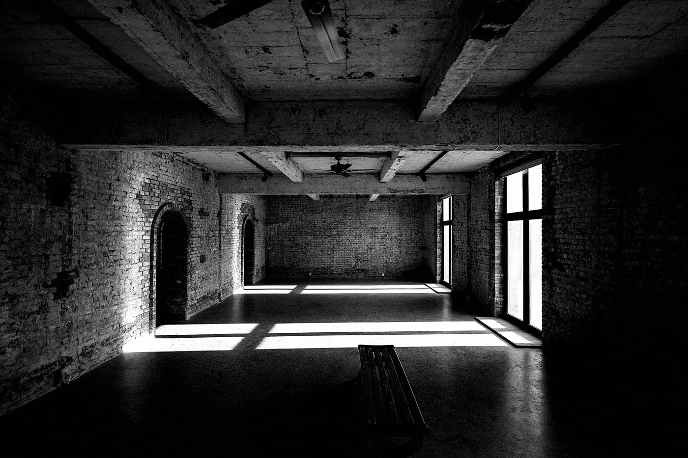 An empty studio with a wooden floor and sunlight from tall windows
