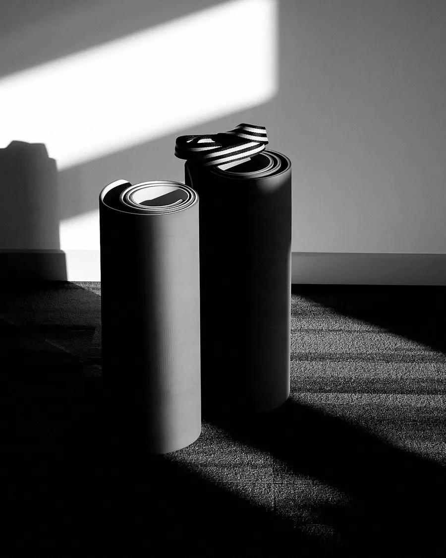 Two rolled yoga mats standing on end in a patch of sunlight