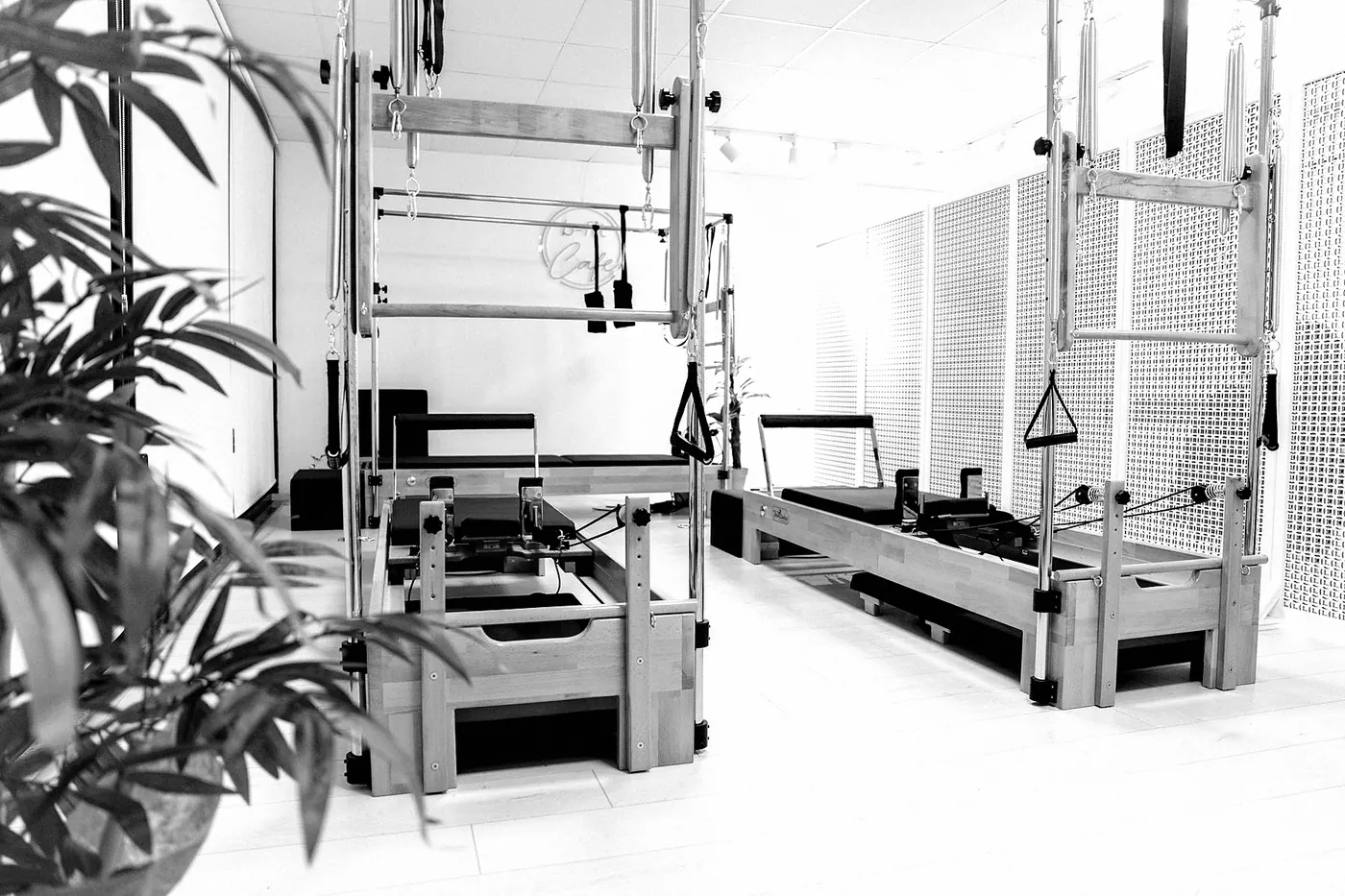 A bright pilates room with a row of reformer machines and towers