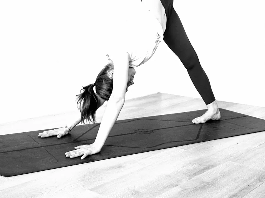A woman in downward dog on a black mat
