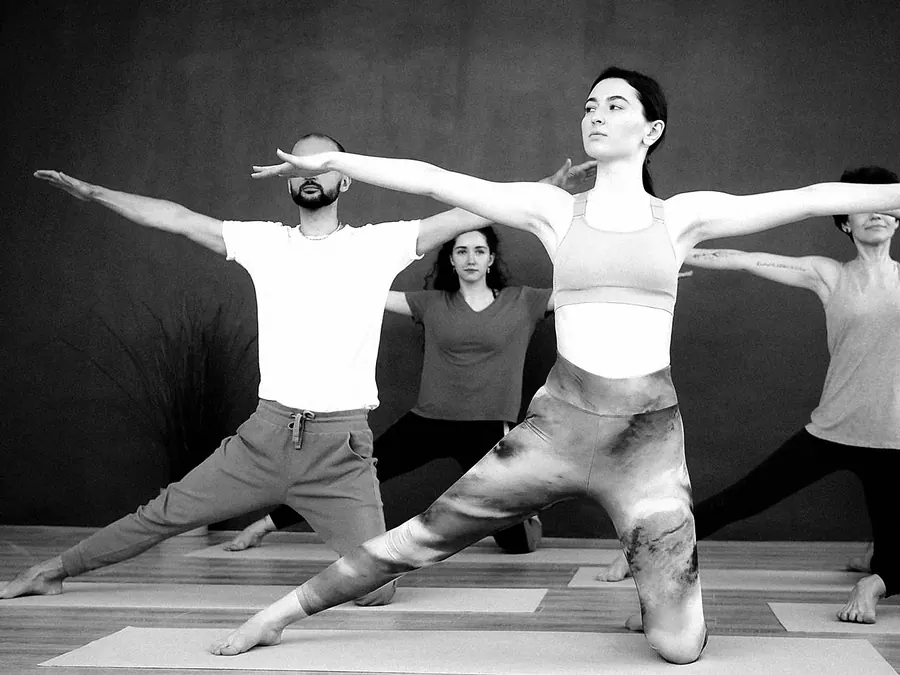 A group in a wide warrior pose with arms stretched out to the sides