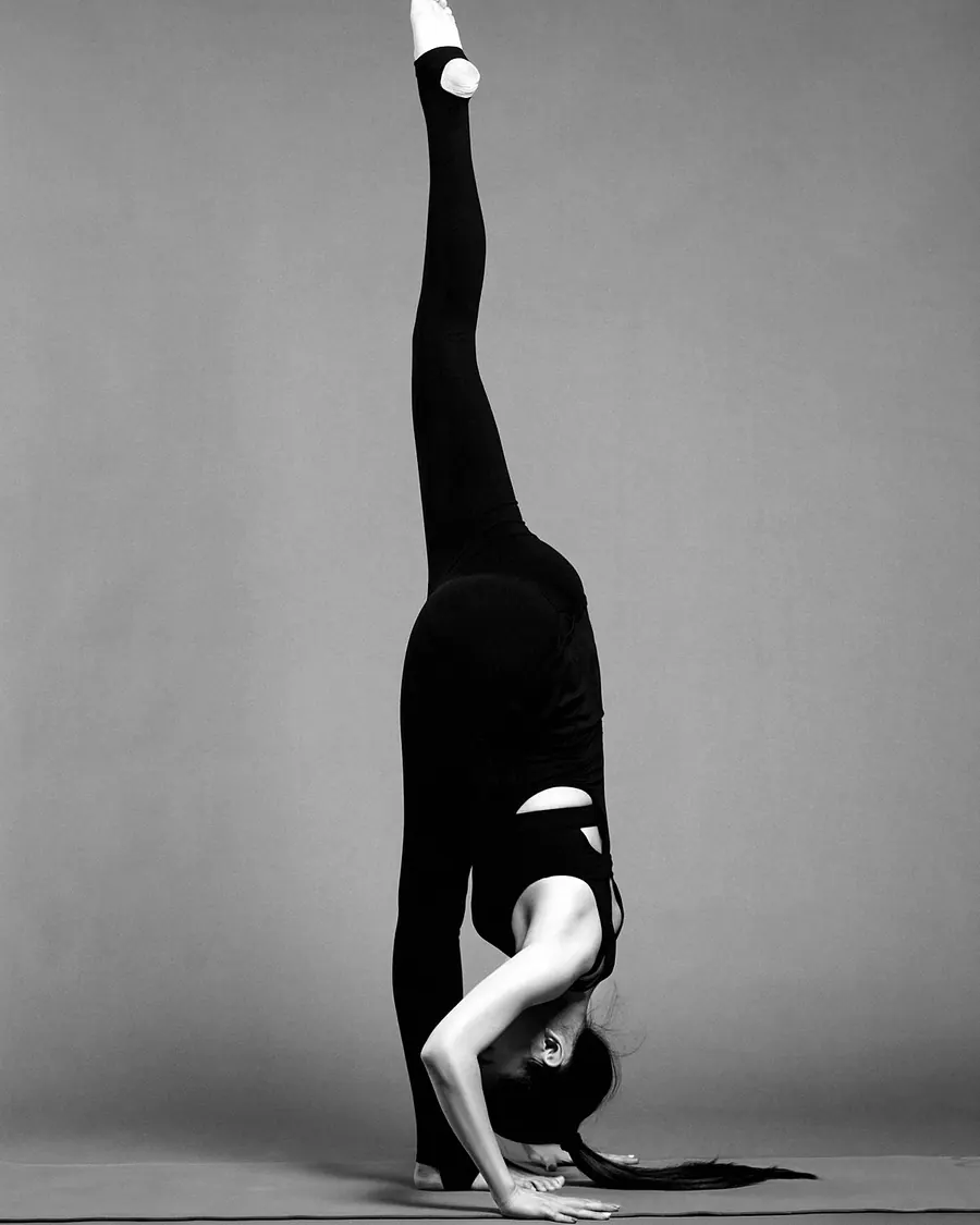 A woman in a standing split with her hands flat on the floor