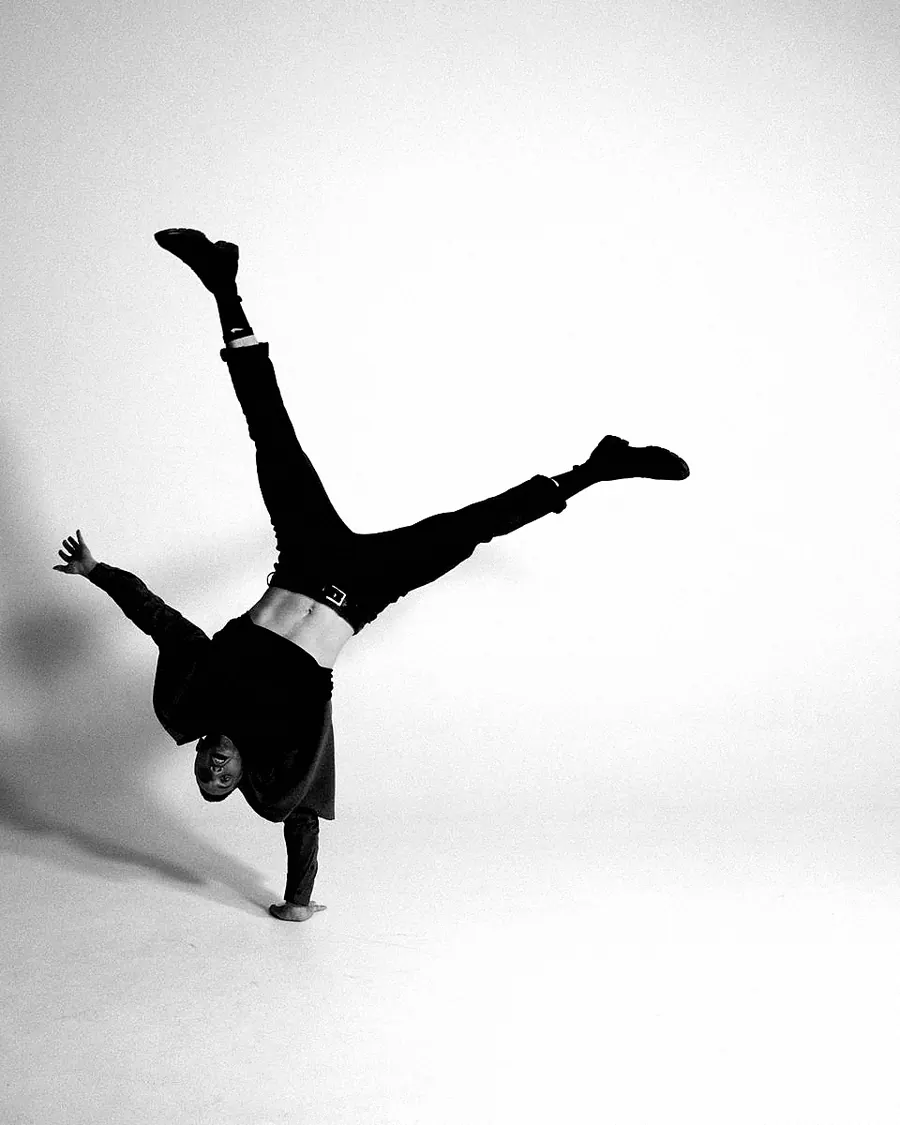 A man turning a one-armed cartwheel on a plain white floor