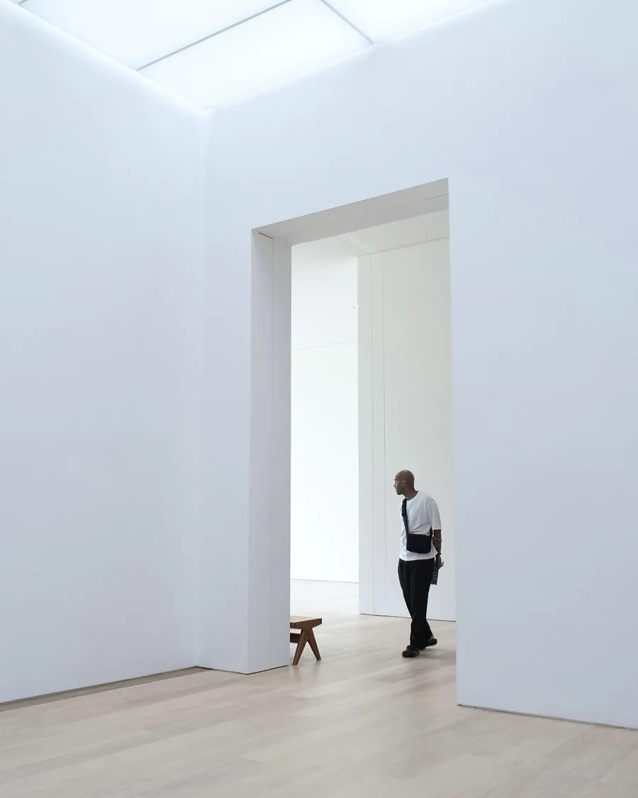 A tall white room with a wide doorway, a visitor walking through