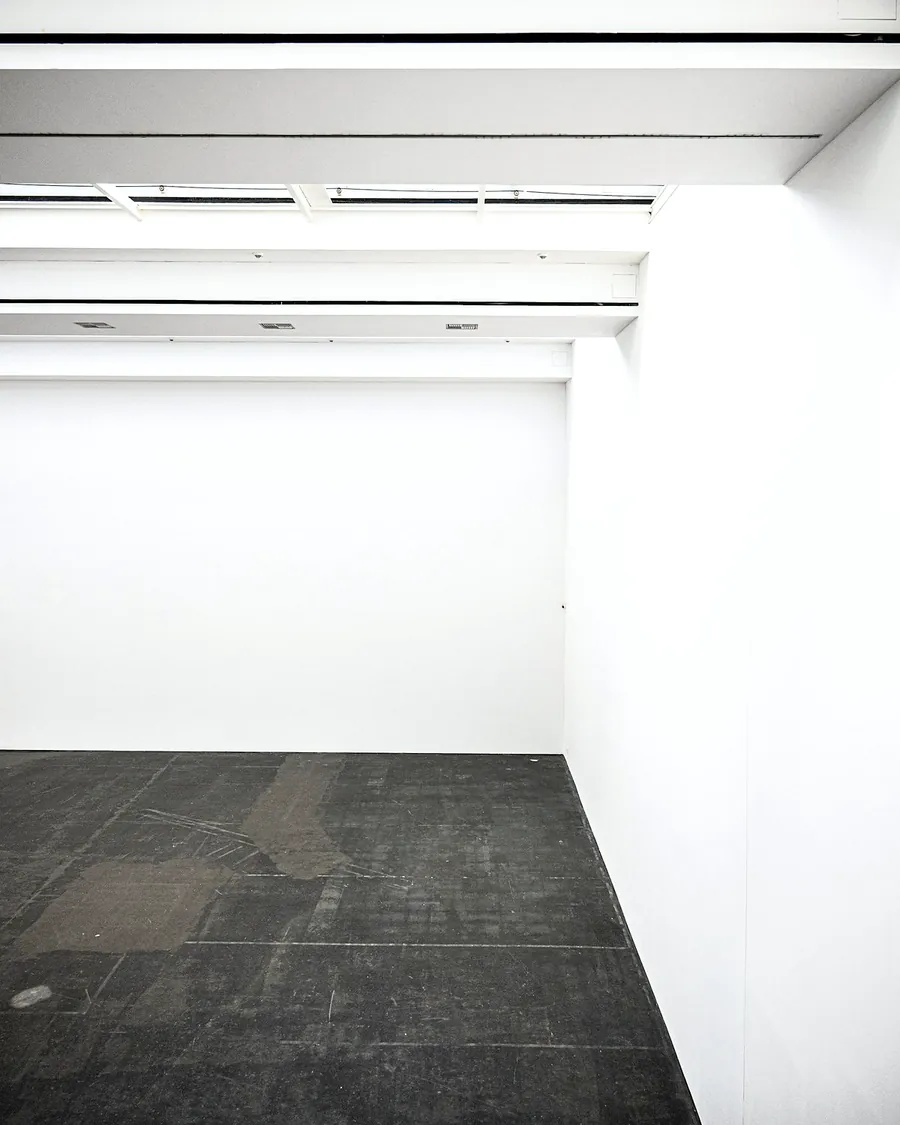 A small white room with a dark floor and a lit ceiling