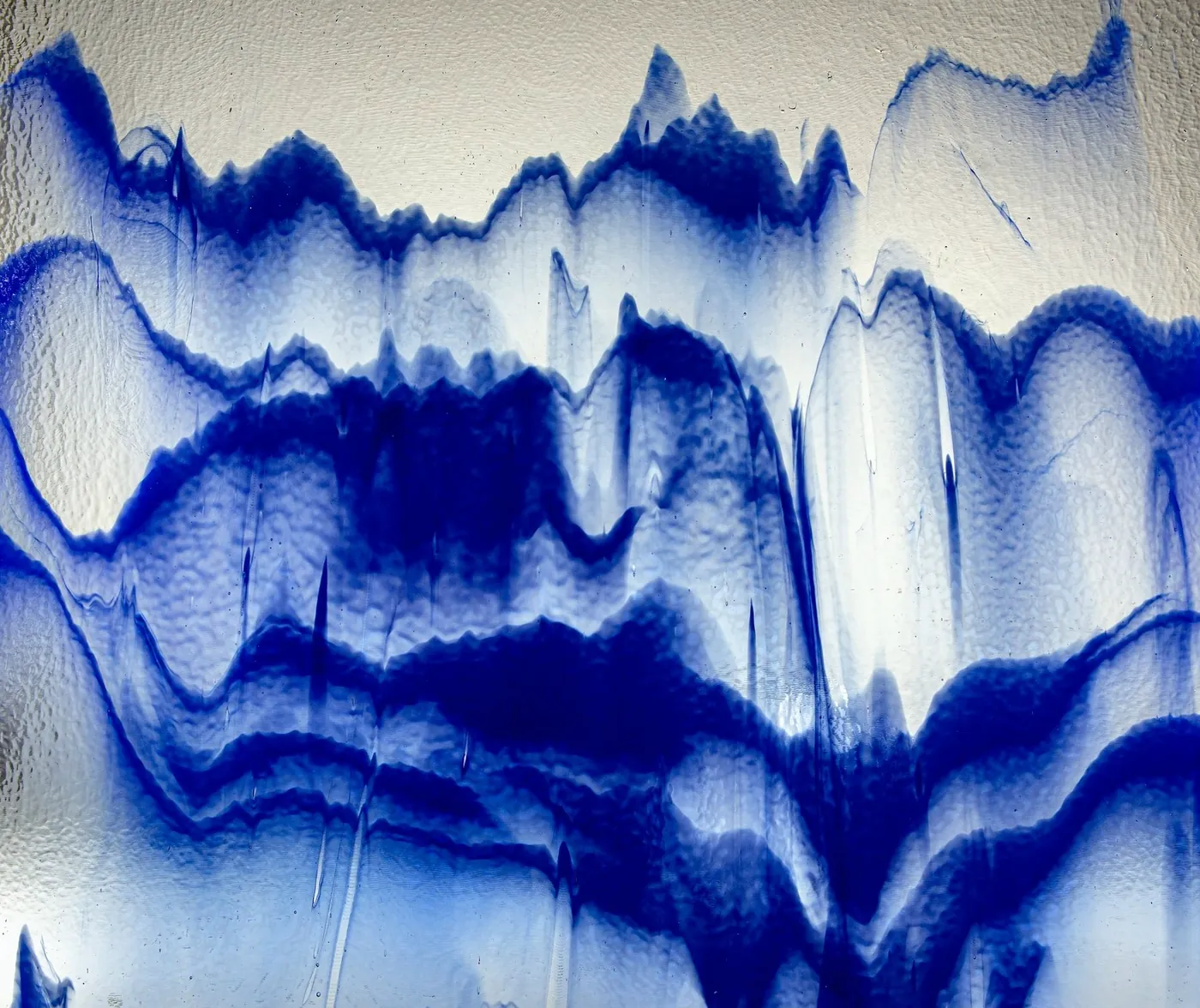 Bands of deep blue ink running down a white ground in ragged layers