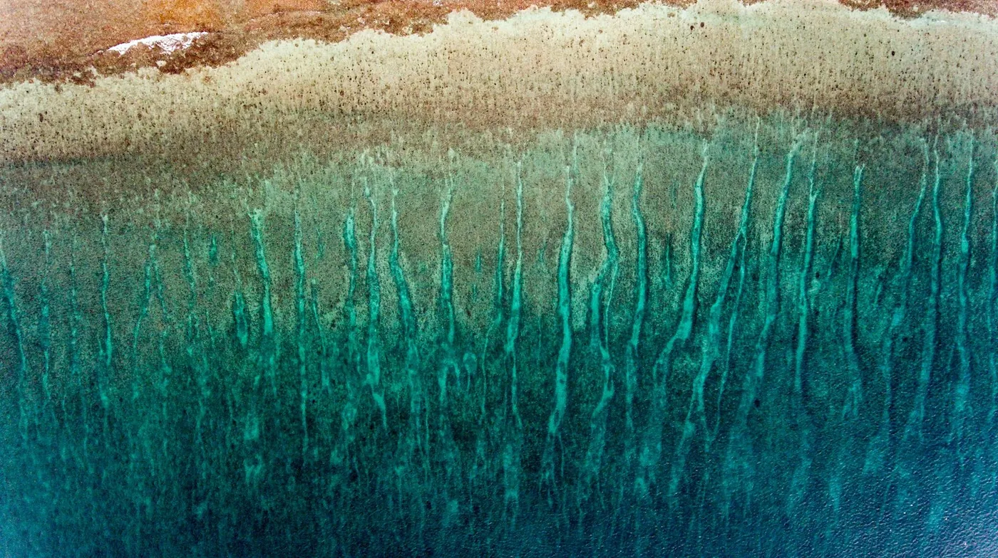 Teal glaze streaking down from a pale crusted band along the top edge