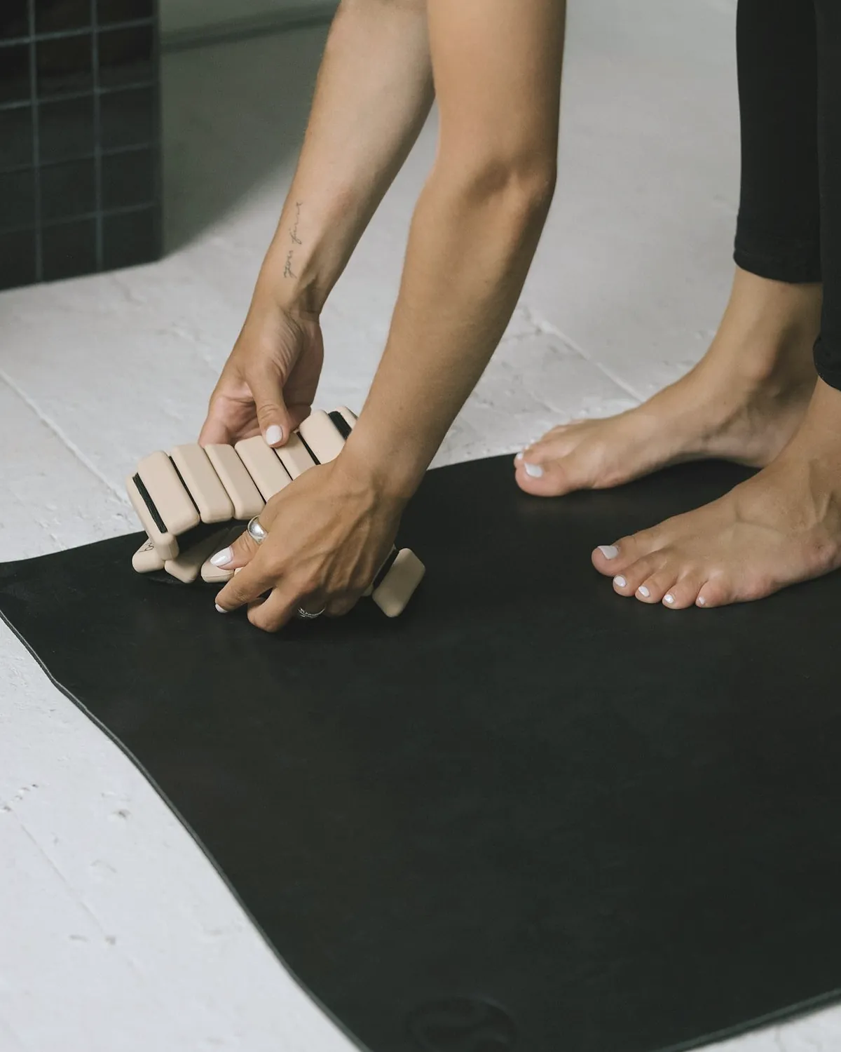 Hands placing two cork blocks at the front of a black mat