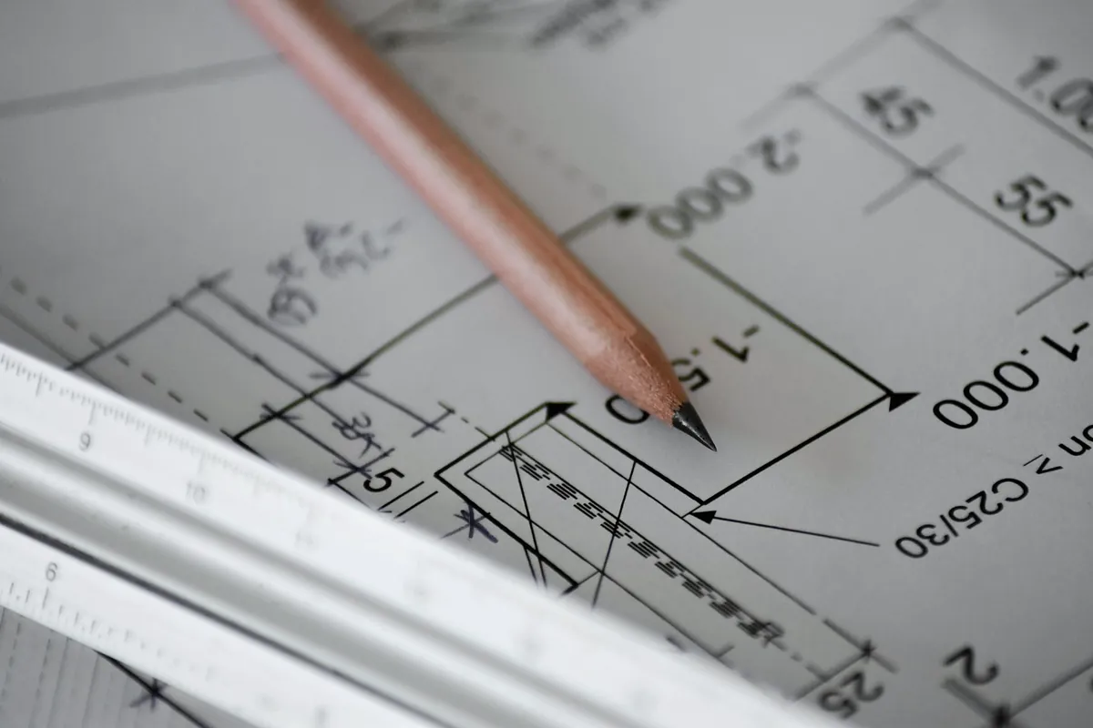 A pencil resting on a construction drawing with dimension lines and level marks