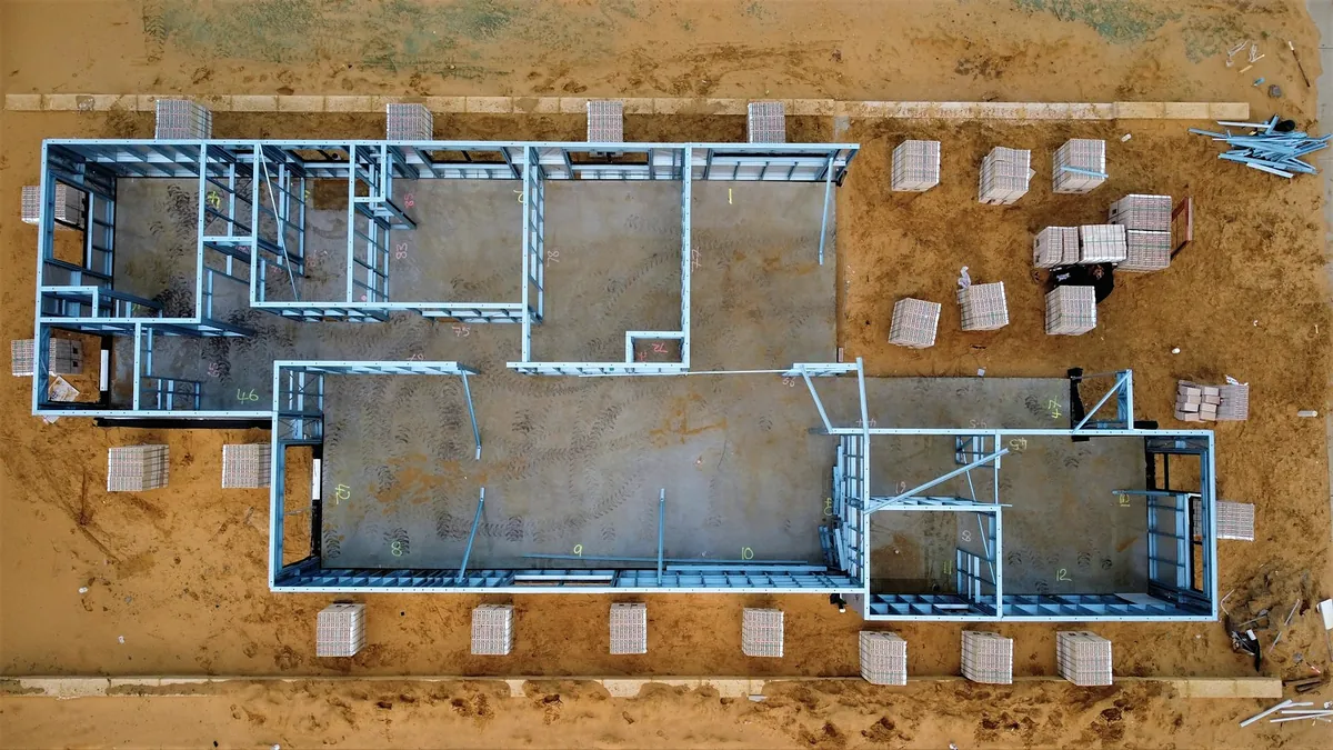 An aerial view of a new house slab with the wall lines set out in blue on red earth