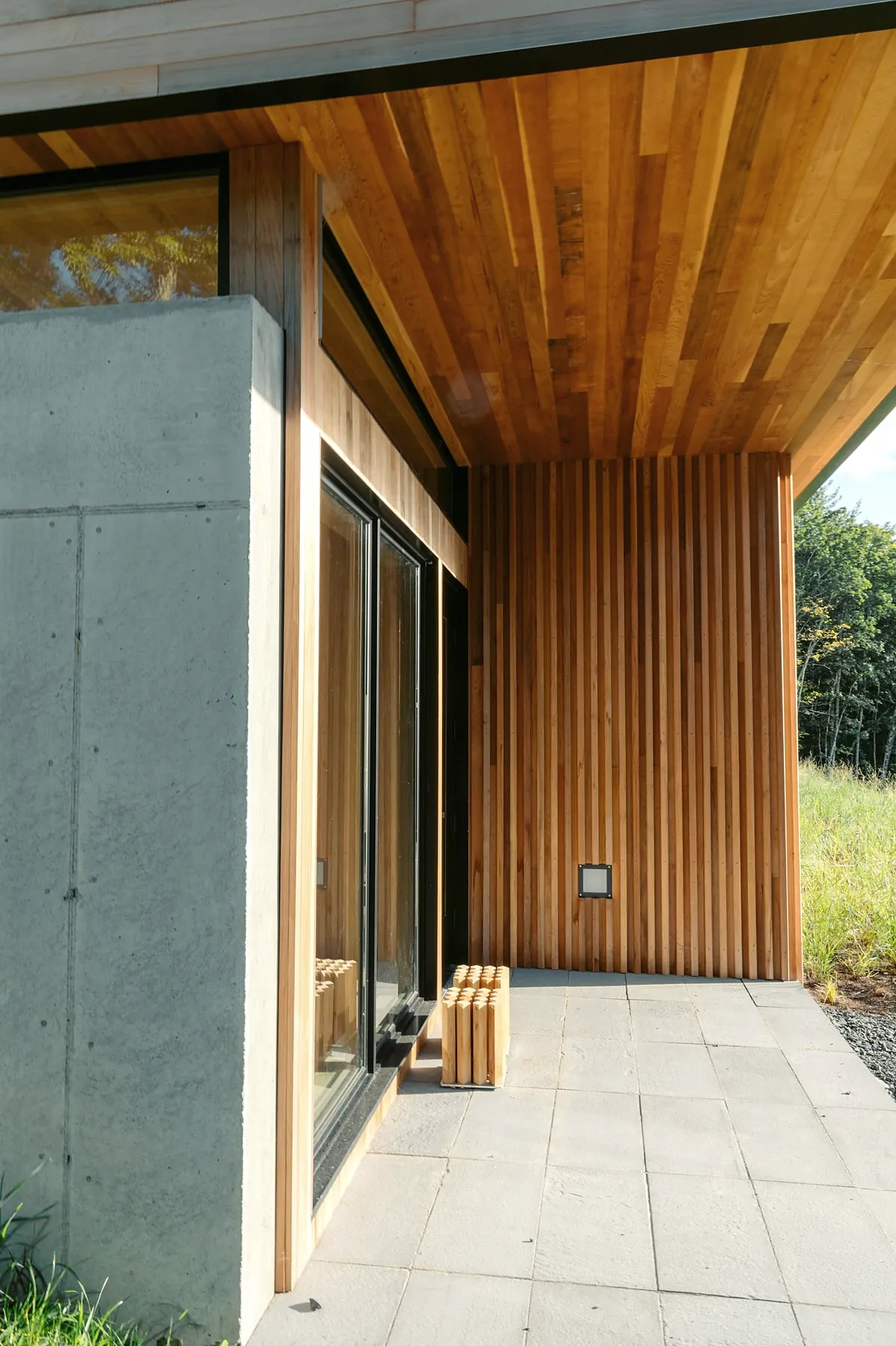 A covered terrace corner with a concrete wall, a timber-lined ceiling and timber boards on the wall