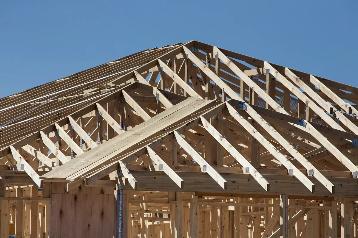 Timber roof trusses on top of a house frame against a blue sky