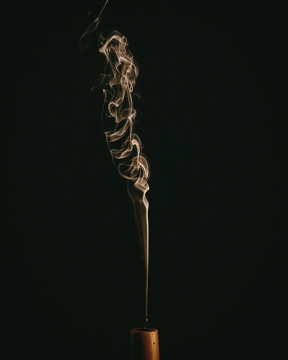 A thin line of smoke rising from a trimmed wick